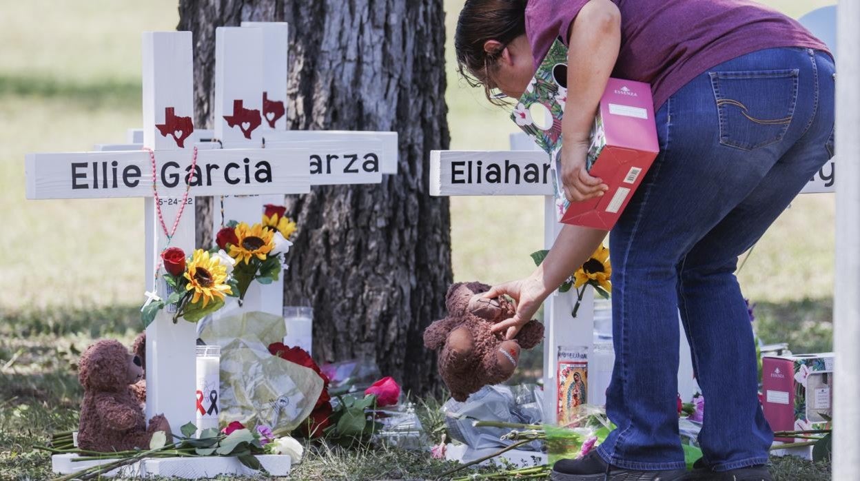 Una mujer deposita un oso de peluche en un memorial improvisado por las víctimas de Texas