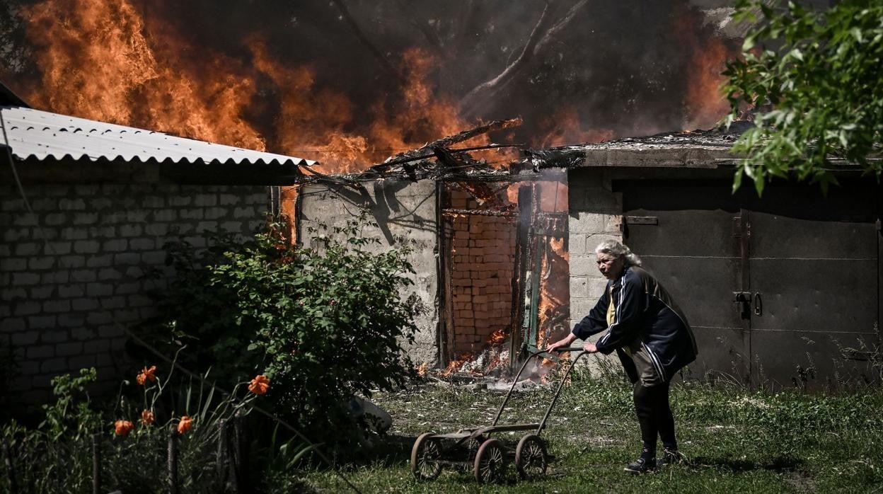 Una mujer junto a una casa en llamas en la ciudad de Lisichansk, en la región del Donbass