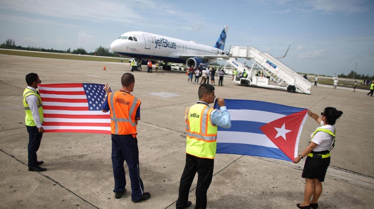 El personal de tierra sostiene banderas de Estados Unidos y Cuba