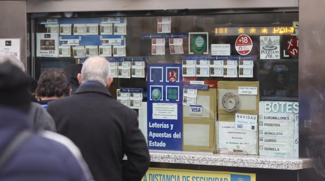 Varias personas en una administración de lotería ubicada en la Puerta del Sol esperando para comprar décimos para el Sorteo Extraordinario de la Lotería de Navidad