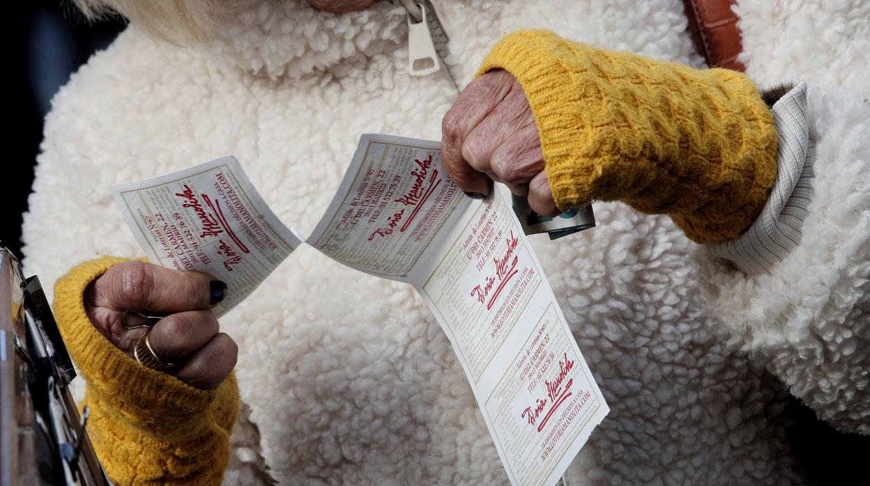 Una lotera entrega una tira de boletos de la Lotería del Niño