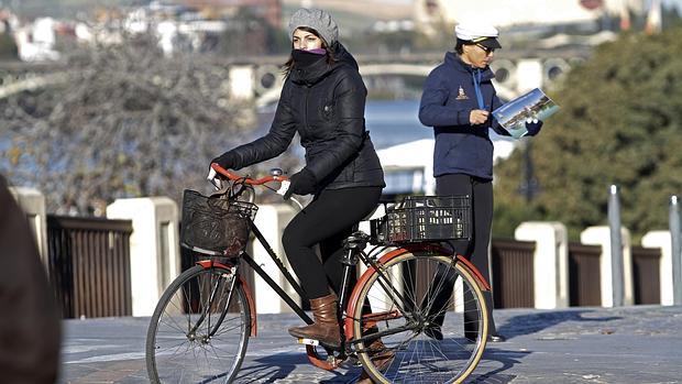 Una joven pasea muy abrigada en bicicleta por Sevilla