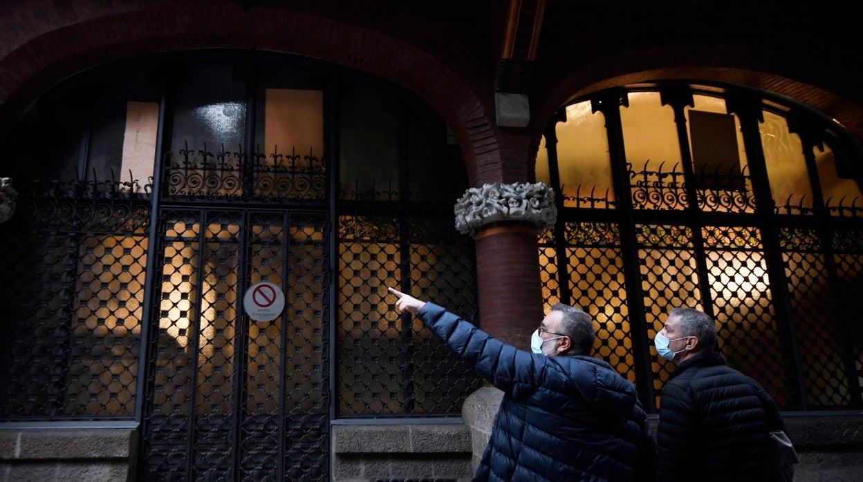 Dos hombres observan los daños causados en la fachada del Palau