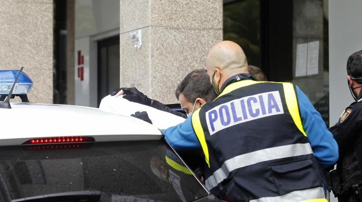 Agentes de la policía introduciendo a un detenido en el coche (Foto de archivo)