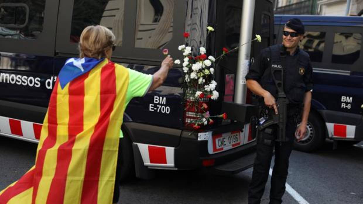 Una manifestante independentista ofrece flores a un policía nacional en las calles de Barcelona