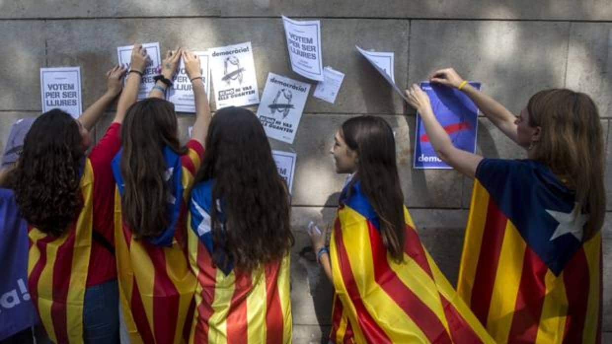 Varias estudiantes enganchan carteles en la pared de la Universidad de Barcelona