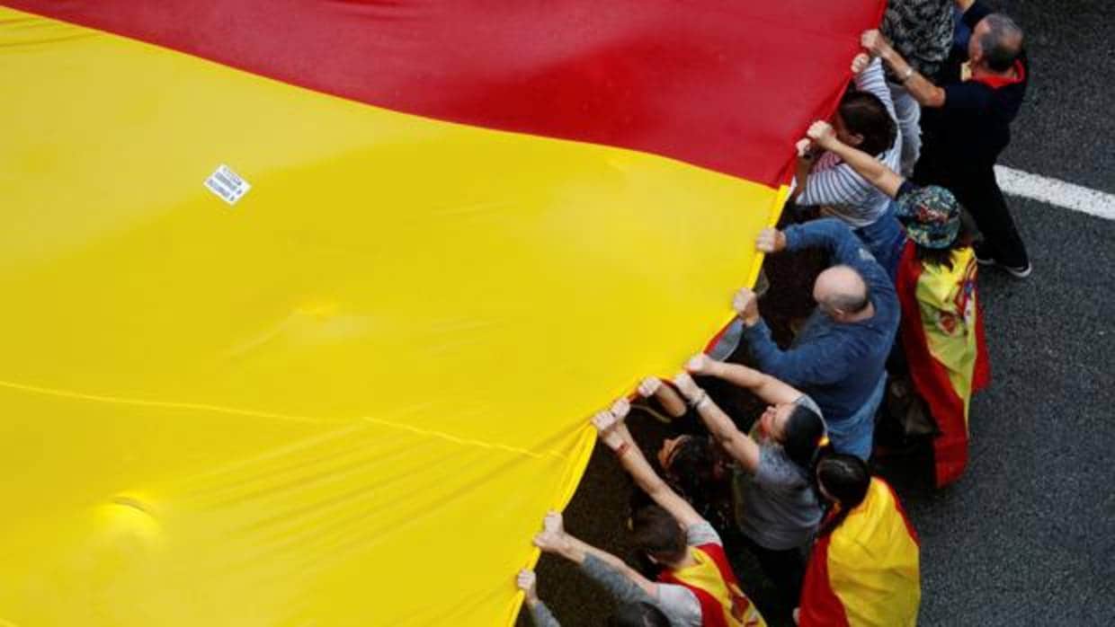 Varios manifestantes sujetan una bandera española de gran tamaño