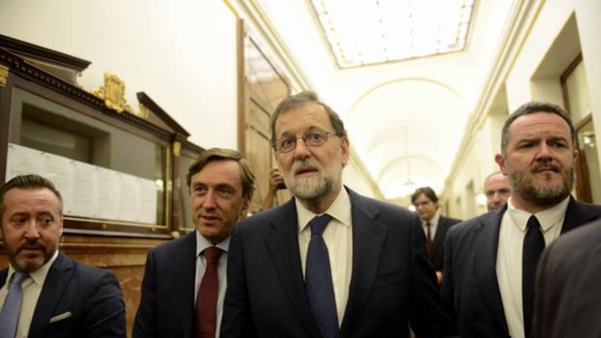 El presidente del Gobierno, Mariano Rajoy (centro), en el pasillo del Congreso