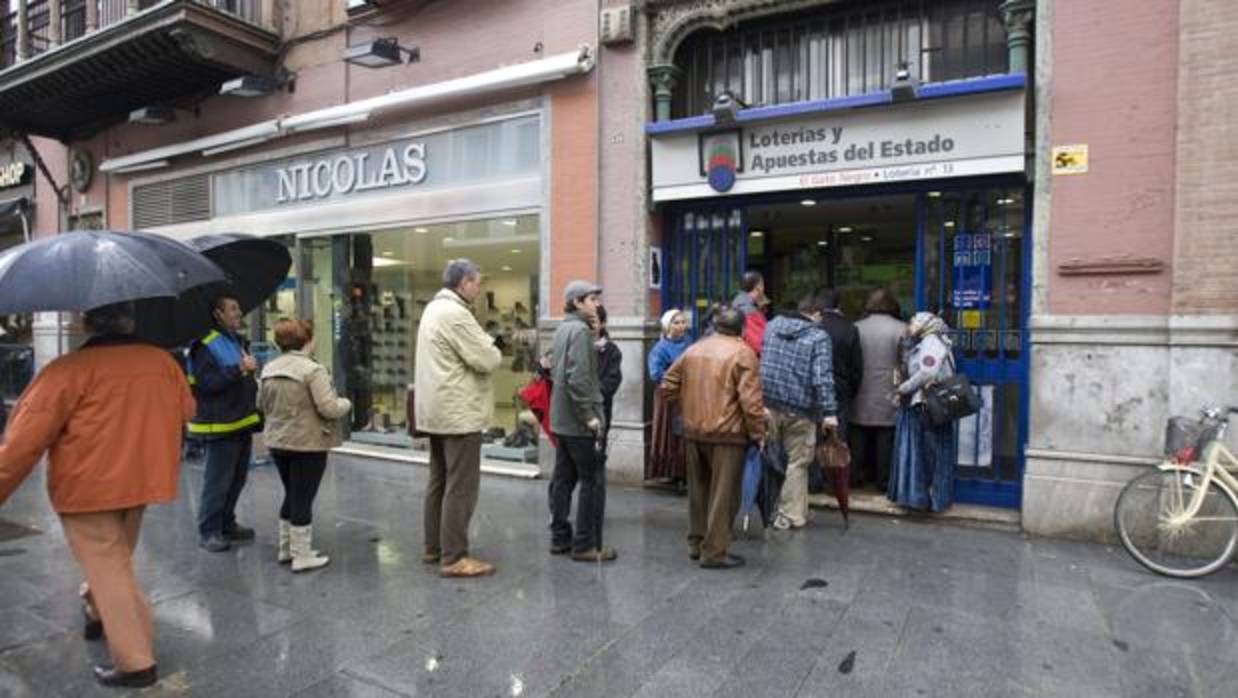 Personas haciendo cola para comprar un décimo de Navidad en El Gato Negro