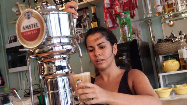 Una camarera tira una cerveza en un bar de la calle Regina, en Sevilla