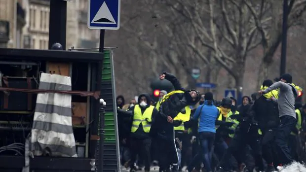 Un manifestante lanza un objeto contra un agente de policía durante las protestas de los chalecos amarillos