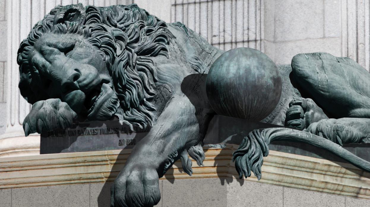 Uno de los leones de la entrada del Congreso de los Diputados tirado y con gesto de agotamiento.