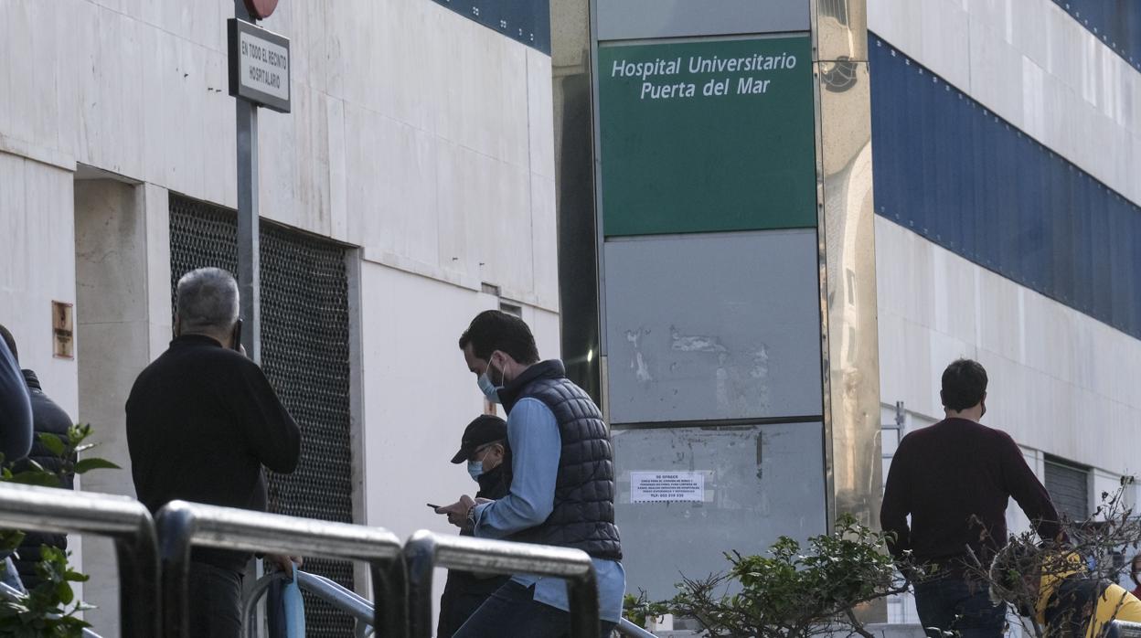 Gente con mascarillas en el Hospital Puerta del Mar.