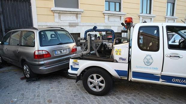 Retirada de un vehículo por parte del servicio municipal de grúa, en Cádiz