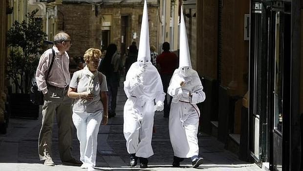 Unos turistas observan a unos penitentes de Cádiz