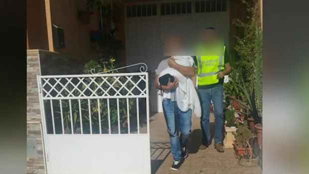 Uno de los detenidos sale de la casa de Vícar con la niña en sus brazos.