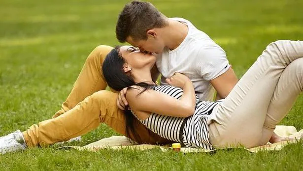 Dos jóvenes se besan en el parque.