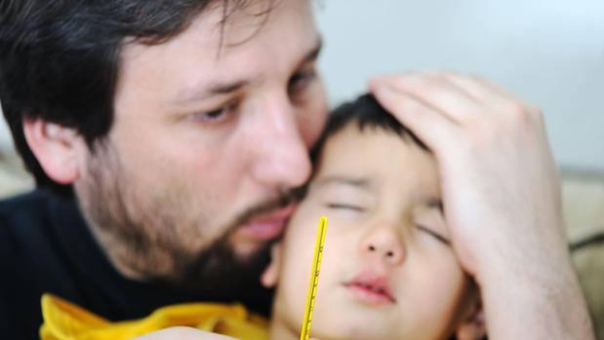 Un padre cuida a su hijo, enfermo de gripe.