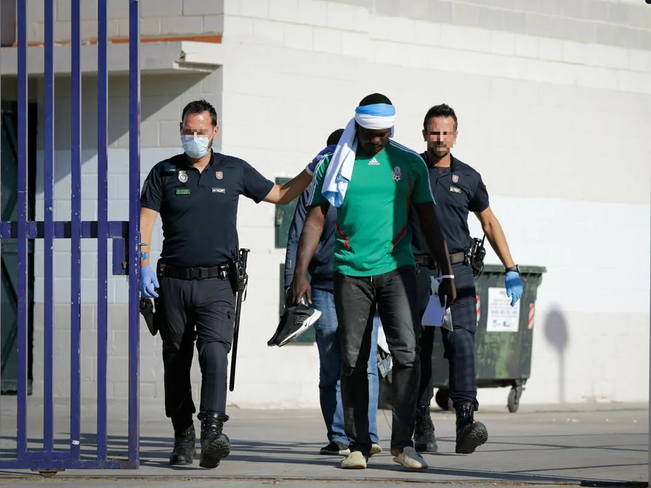 Agentes de la Policía Nacional trasladan a uno de los inmigrantes que han sido acogidos a su llegada en el pabellón de Algeciras