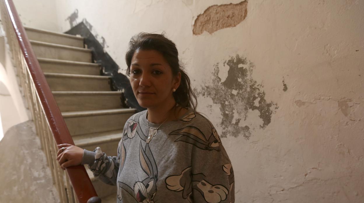 Vanesa, en la escalera de su vivienda con múltiples humedades en sus paredes.