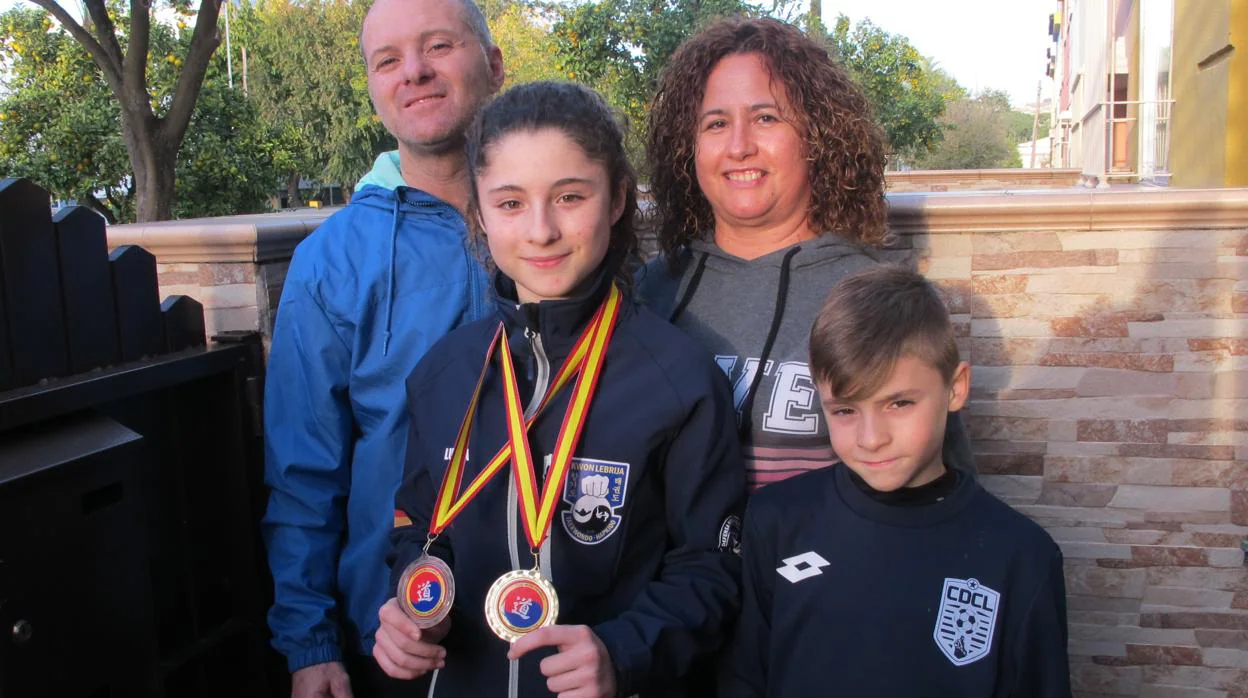Lucía Elías muestra las medallas ganadas en Cáceres, acompañada de su familia