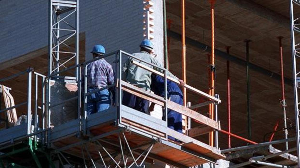 Unos obreros encima del andamio de un edificio