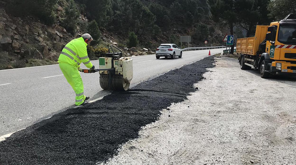 Un operario asfalta un tramo de arcén de una carretera