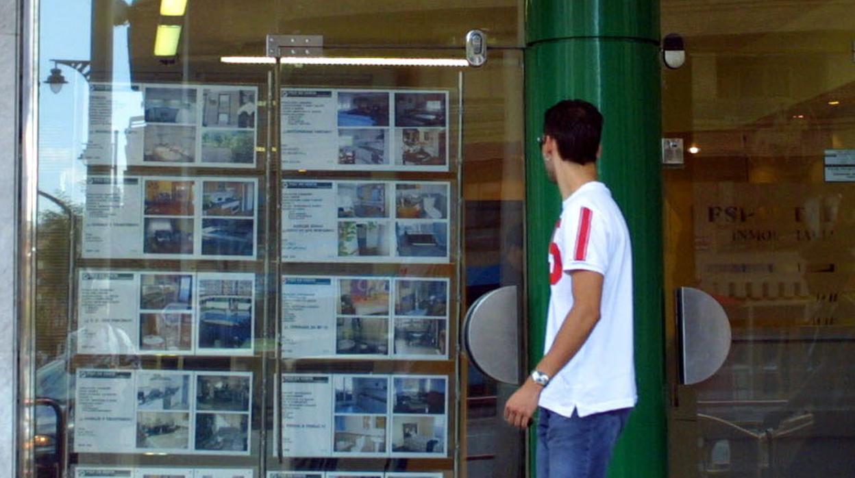 Un joven se detiene en el escaparate de una inmobiliaria en Cádiz.