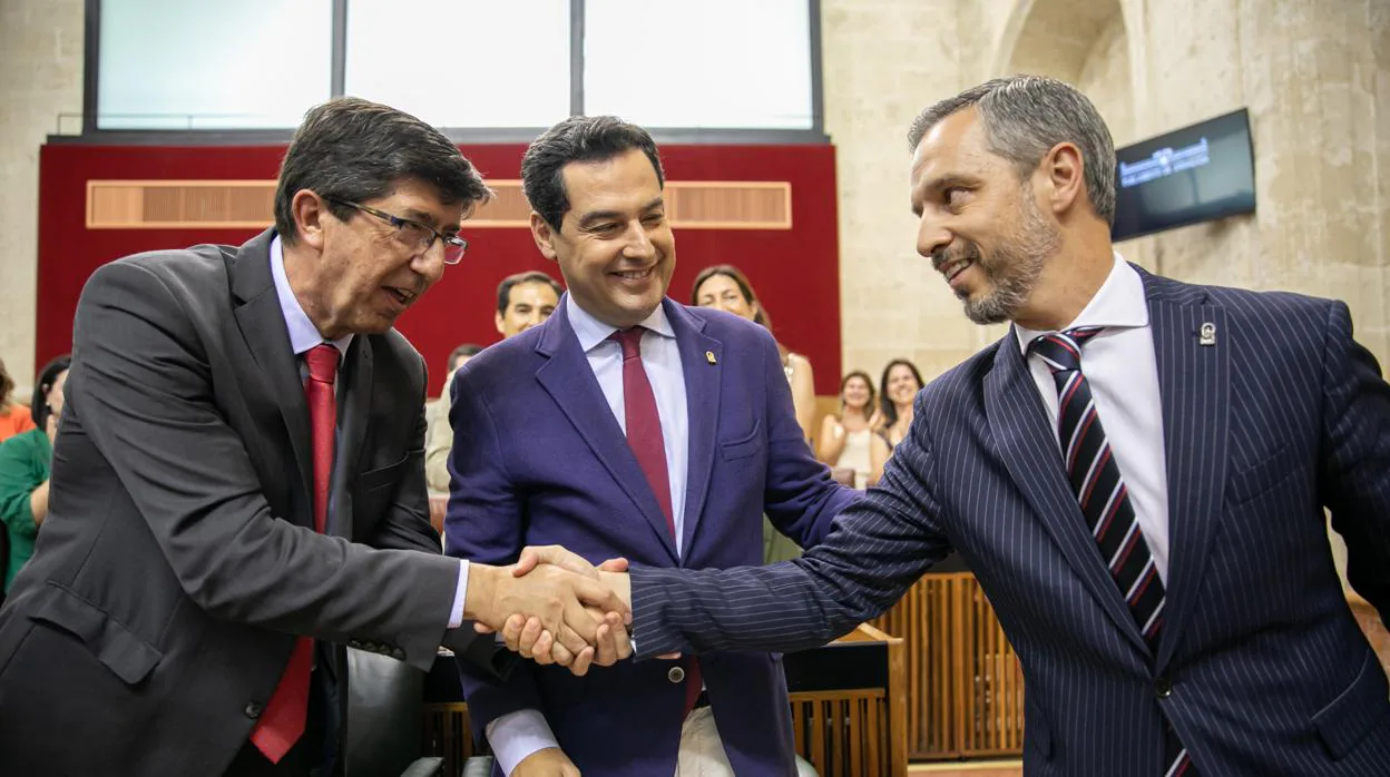 Juan Marín y Juan Bravo se felicitan bajo la mirada de Juanma Moreno