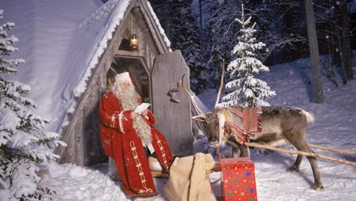 Papá Noel en la puerta de su casa leyendo cartas.