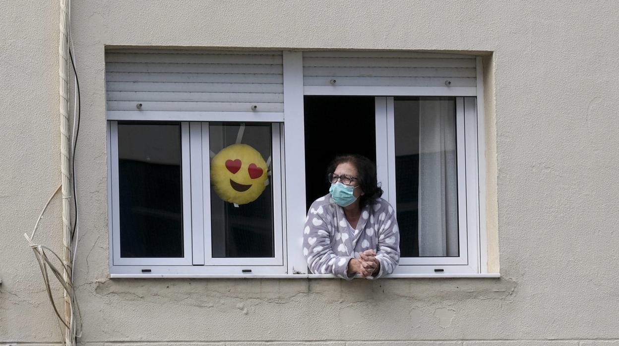 Una mujer con mascarilla asomada a la ventana de su casa durante el Estado de Alarma..