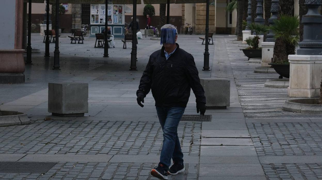 Un ciudadano protegido camina por la plaza San Juan de Dios de Cádiz.