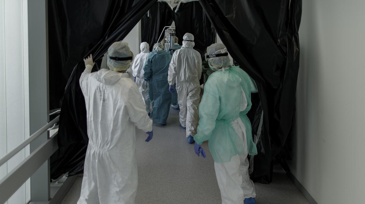 Personal sanitario totalmente protegido trasladan a un paciente ingresado en la Unidad de Cuidados Intensivos del Hospital Infanta Sofía en San Sebastián de los Reyes (Madrid).