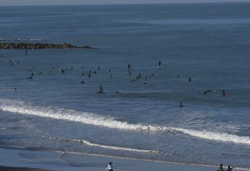 La playa, llena de surferos.