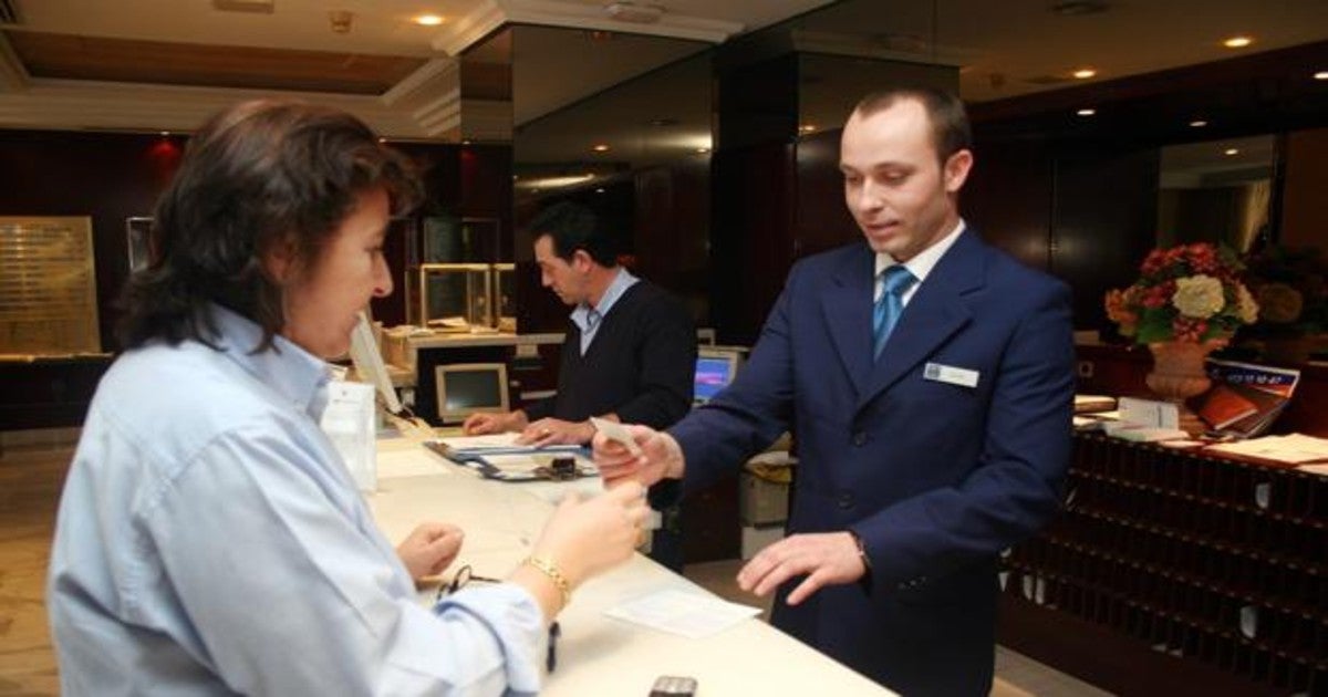 Un recepcionista entrega las llaves de la habitación a una clienta.