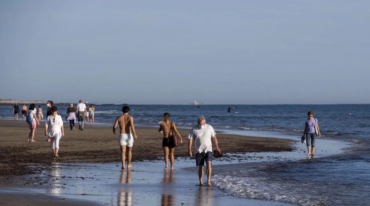 Personas paseando por la orilla de la playa en Cádiz.