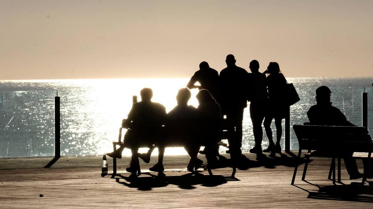 Varias personas disfrutan de una puesta de sol en Cádiz