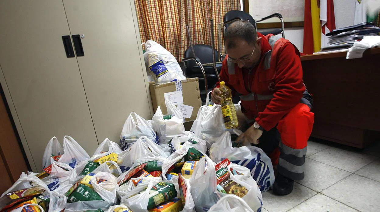Un voluntario de Cruz Roja prepara bolsas de alimentos en la sede de Cruz Roja.