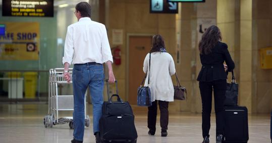 Varios pasajeros, por el interior del aeropuerto.