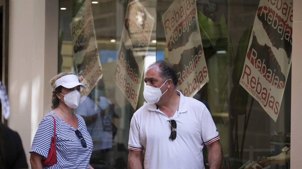 Varias personas andan por delante de una tienda por las calles más comerciales de Cádiz.