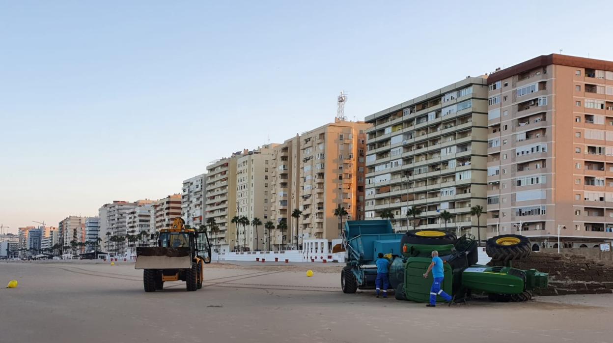 La cabeza del camión del servicio de playas volcado sobre la arena.