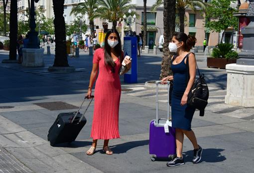 Dos turistas con mascarilla y maleta, en Cádiz.