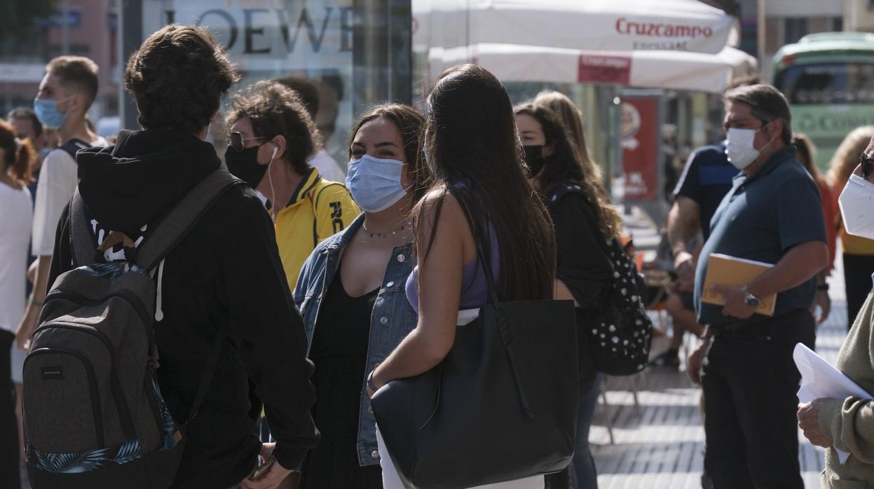 Personas con mascarilla esperan el autobus en Cádiz capital.