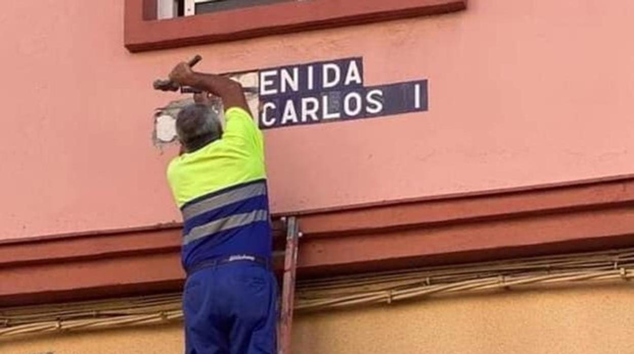 Un operario retirando el nombre de la avenida Juan Carlos I, ahora de la Sanidad Pública.