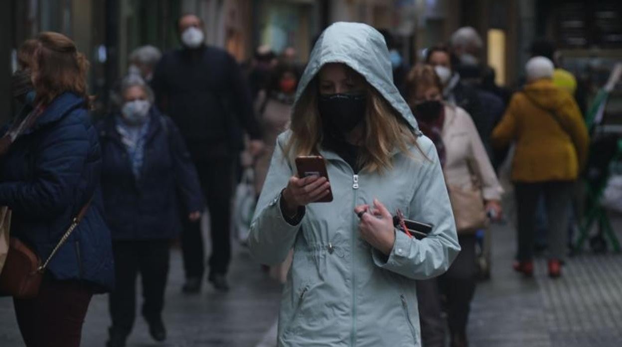 Una gaditana con mascarilla consulta su móvil en Cádiz capital.