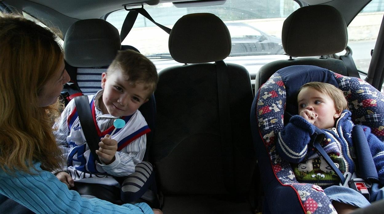 Imagen de archivo de una madre colocando los sinturones a sus hijos en el coche..