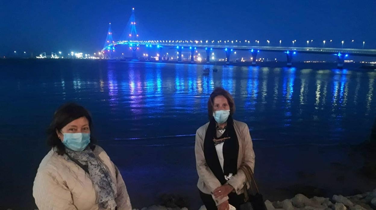 Dos enfermeras del hospital Puerta del Mar con el puente de fondo iluminado por el Día de la Enfermera