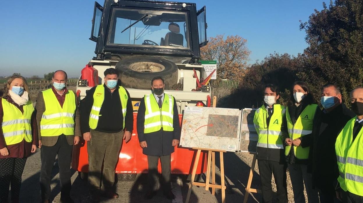 Autoridades locales, autonómicas y militares ante una máquina de reparación del firme de la carretera de la base de Morón