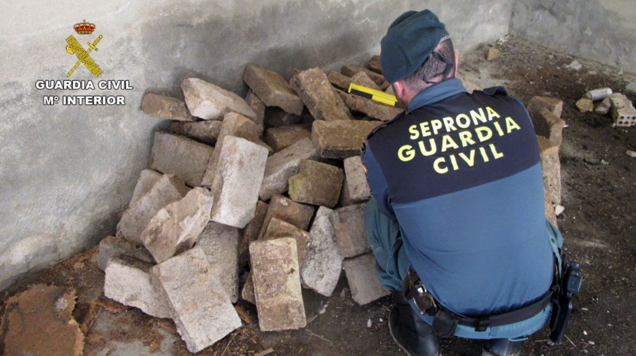 Un agente de la Guardia Civil inspecciona los ladrillos que se llevó este vecino de Osuna a su casa