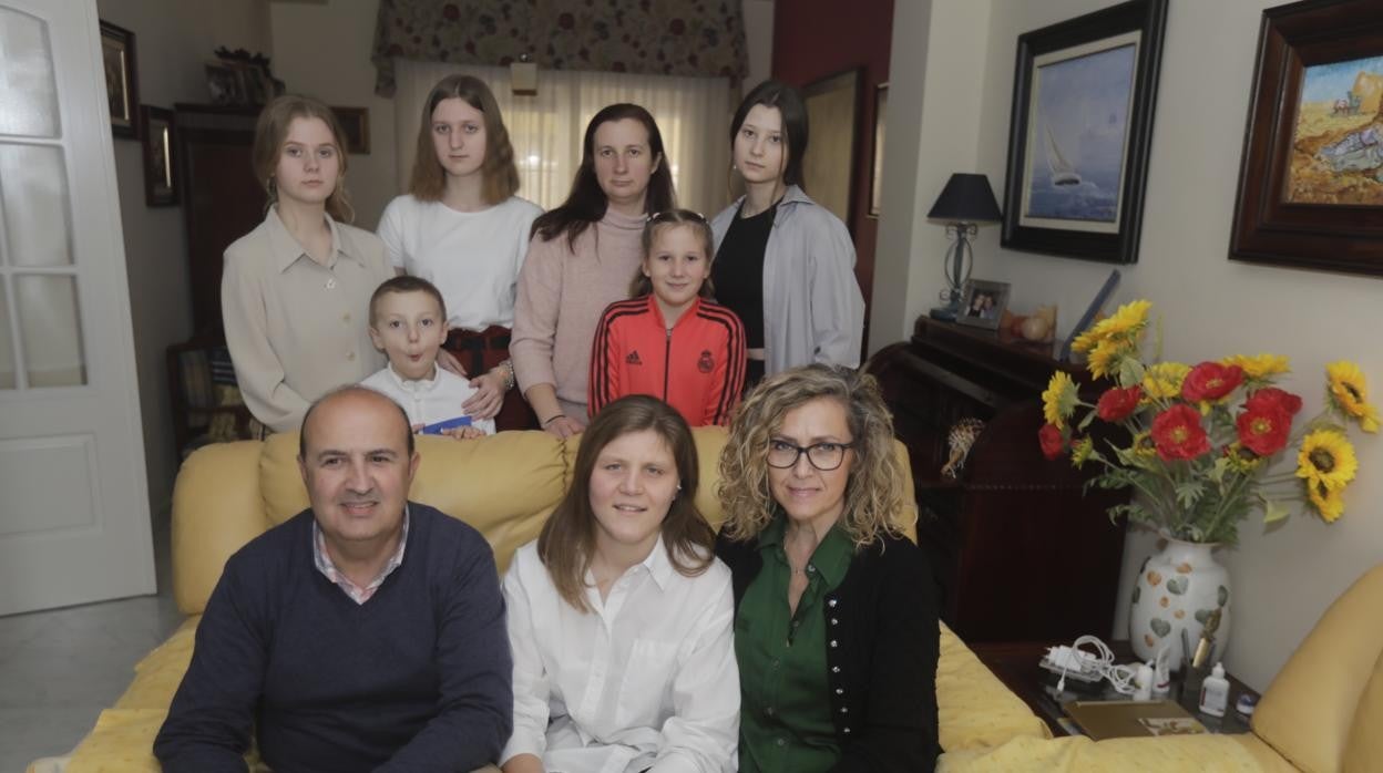 Dos familias unidas. Carmen y Andrés y su hija en primer término. Katya, su madre y sus hermanos, todos en el salón de su nueva casa tras salir de Ucrania.